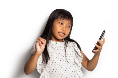 Mutlu Asyalı küçük kız beyaz arka planda akıllı telefon kullanıyor.
