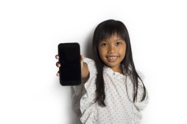 Mutlu Asyalı küçük kız beyaz arka planda akıllı telefon kullanıyor.