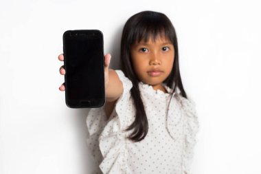 Mutlu Asyalı küçük kız beyaz arka planda akıllı telefon kullanıyor.