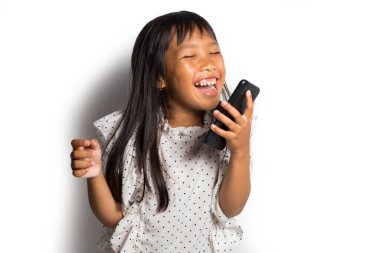 Mutlu Asyalı küçük kız beyaz arka planda akıllı telefon kullanıyor.