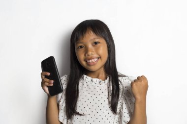 Mutlu Asyalı küçük kız beyaz arka planda akıllı telefon kullanıyor.