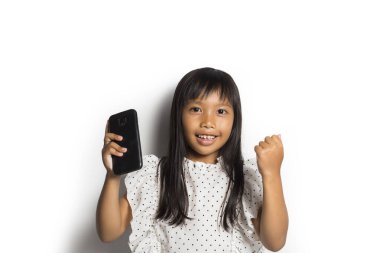 Mutlu Asyalı küçük kız beyaz arka planda akıllı telefon kullanıyor.