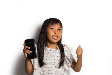 Mutlu Asyalı küçük kız beyaz arka planda akıllı telefon kullanıyor.