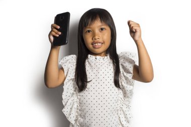 Mutlu Asyalı küçük kız beyaz arka planda akıllı telefon kullanıyor.