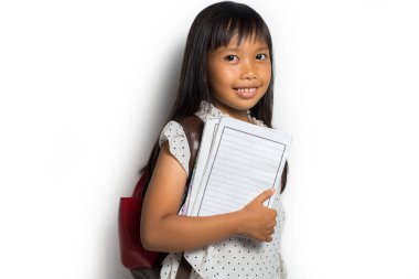 Güzel Asyalı küçük kız elinde okul çantasıyla kitap tutuyor. Okul için eğitici konsept.