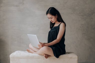 Asyalı güzel kadın dizüstü bilgisayarla düşünüyor.