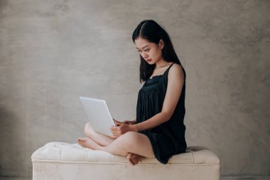 Asyalı güzel kadın dizüstü bilgisayarla düşünüyor.