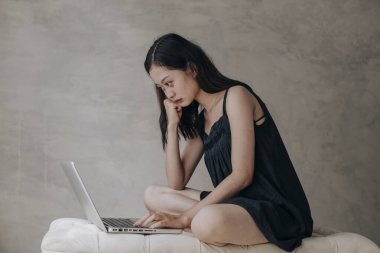 Asyalı güzel kadın dizüstü bilgisayarla düşünüyor.