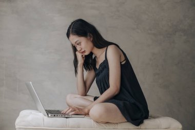 Asyalı güzel kadın dizüstü bilgisayarla düşünüyor.