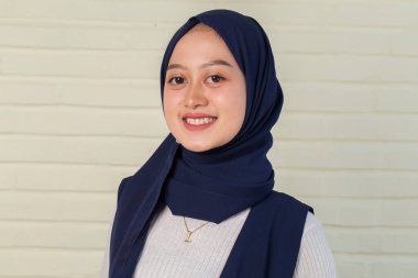 Asyalı genç Müslüman kadın, kollarını kavuşturmuş kaşkollu gülümseme.