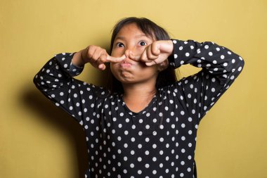 Asyalı küçük kız kötü bir koku yüzünden burnunu tutuyor.