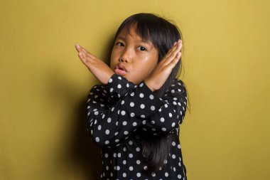 Asyalı küçük kız elleriyle dur hareketi yapıyor.