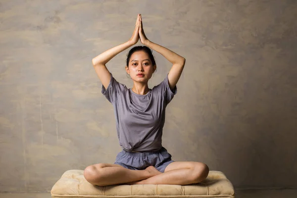 Asian woman do yoga practice meditating indoors, lotus position. No stress, mindfulness, inner balance concept