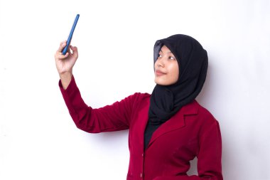 Cep telefonuyla selfie çeken mutlu Asyalı kadın. Beyaz stüdyo arka planında poz veren gülümseyen kız portresi.