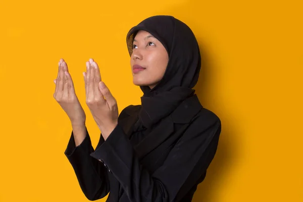 年轻的亚裔穆斯林妇女 头戴头巾 在黄色背景下祈祷 — 图库照片