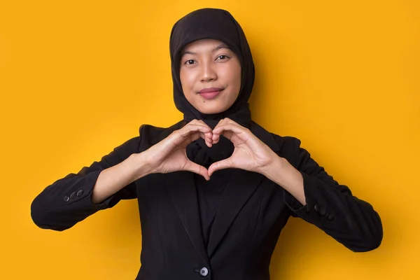 肖像アジアのイスラム教徒の女性は黄色の背景に孤立したハートサインを示すヒジャーブを身に着けて — ストック写真