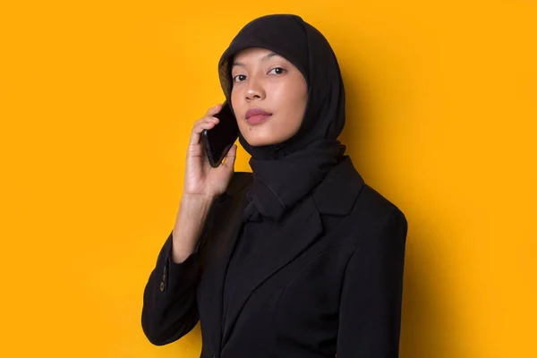 年轻的亚洲美女头戴头巾 背景是黄色 在电话里说话 — 图库照片