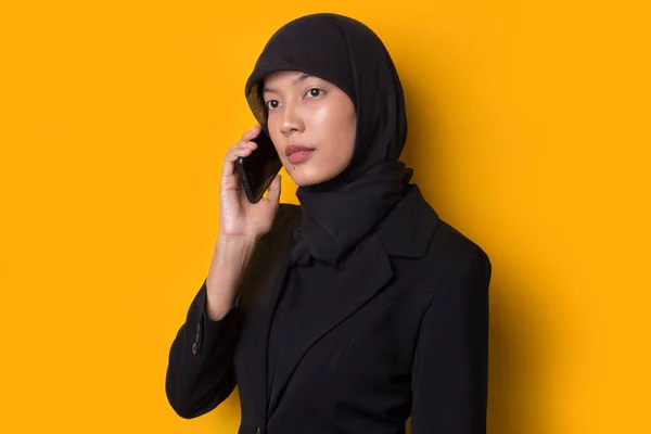 年轻的亚洲美女头戴头巾 背景是黄色 在电话里说话 — 图库照片