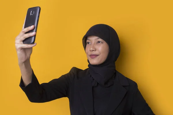 快乐的亚洲女人在头巾与手机制造自拍 关于黄色背景 — 图库照片