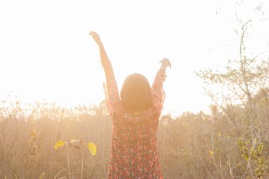 Genç kadın rahatlatıcı yaz günbatımı gökyüzü açık.