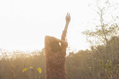 Genç kadın rahatlatıcı yaz günbatımı gökyüzü açık.