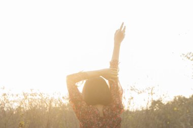 Genç kadın rahatlatıcı yaz günbatımı gökyüzü açık.