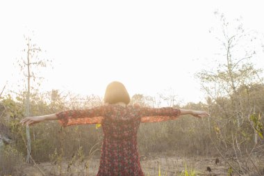 Genç kadın rahatlatıcı yaz günbatımı gökyüzü açık.