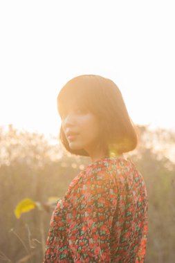 Genç kadın rahatlatıcı yaz günbatımı gökyüzü açık.