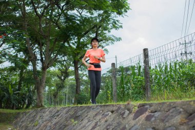 Genç Asyalı bir kadının portresi. Parkta egzersiz yapıyor, koşuyor.