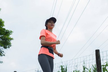 Genç Asyalı bir kadının portresi. Parkta egzersiz yapıyor, koşuyor.