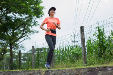 Genç Asyalı bir kadının portresi. Parkta egzersiz yapıyor, koşuyor.