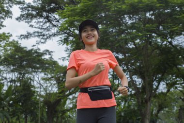 Genç Asyalı bir kadının portresi. Parkta egzersiz yapıyor, koşuyor.