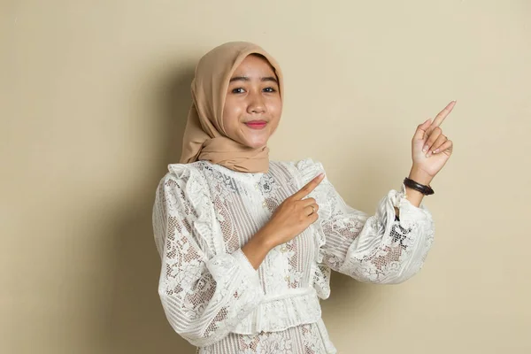 ヒジャーブを身に着けている若いアジアのイスラム教徒の女性は 異なる方向に指で自信を持って指して笑っている 広告のコピースペース — ストック写真