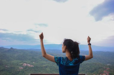 Dağ zirvesinde kollarını açmış tezahürat yapan genç kadın