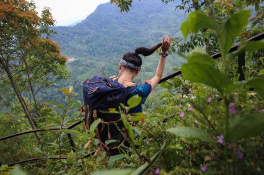 Sırt çantalı genç Asyalı kadın dağa tırmanıyor 