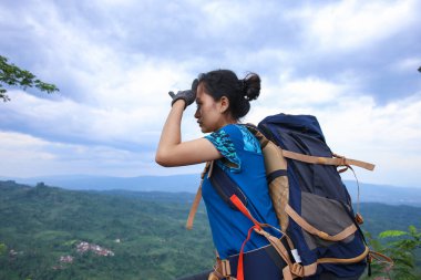 Başarılı Asyalı kadın yürüyüşçü dağın tepesindeki manzaranın tadını çıkar.