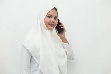Mutlu Asyalı genç Müslüman kadın cep telefonu kullanıyor.