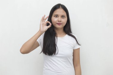 Genç Asyalı kadın gülümsüyor ve el hareketleriyle işaret veriyor..
