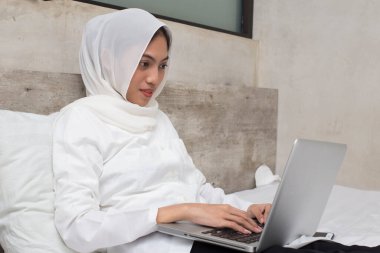 Akıllı Asyalı Müslüman kadın dizüstü bilgisayarını kullanıyor.