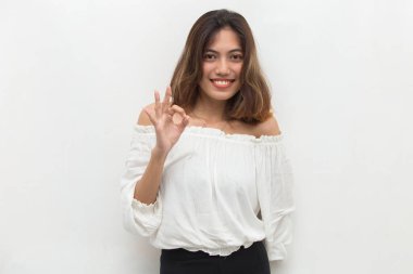 Genç Asyalı kadın gülümsüyor ve el hareketleriyle işaret veriyor..