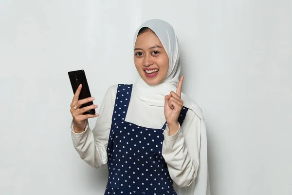 幸せな若いアジア系ムスリム女性は白い背景に孤立した携帯電話を使い — ストック写真