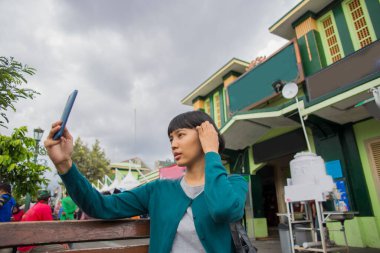 Halka açık yerlerde cep telefonlu genç Asyalı kadın selfie 'si.. 