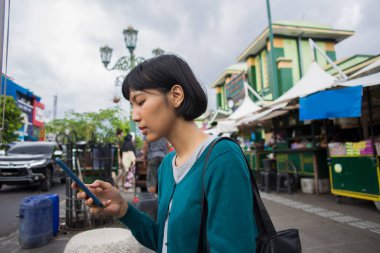 Genç Asyalı kadın halka açık yerlerde cep telefonu kullanıyor.. 