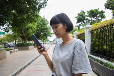 Genç Asyalı kadın halka açık yerlerde cep telefonu kullanıyor.. 