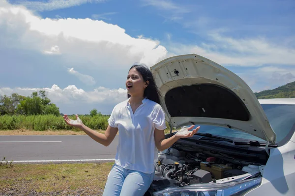 Asian woman need for help  with a broken car with open hood.