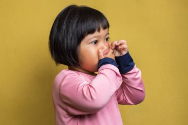 Asyalı küçük kız kötü bir koku yüzünden burnunu tutuyor.