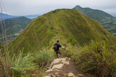 Sırt çantalı bir adam dağlarda tek başına seyahat ediyor.