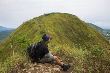 Sırt çantalı bir adam dağlarda tek başına seyahat ediyor.