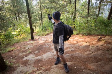 Sırt çantalı turist dağlarda akıllı telefonuyla fotoğraf çekiyor.