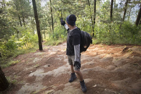 Sırt çantalı turist dağlarda akıllı telefonuyla fotoğraf çekiyor.